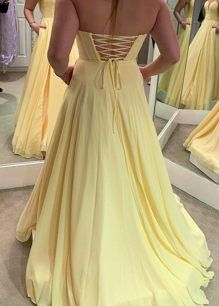 Vestido de fiesta largo amarillo sencillo con bolsillos y espalda con cordones.