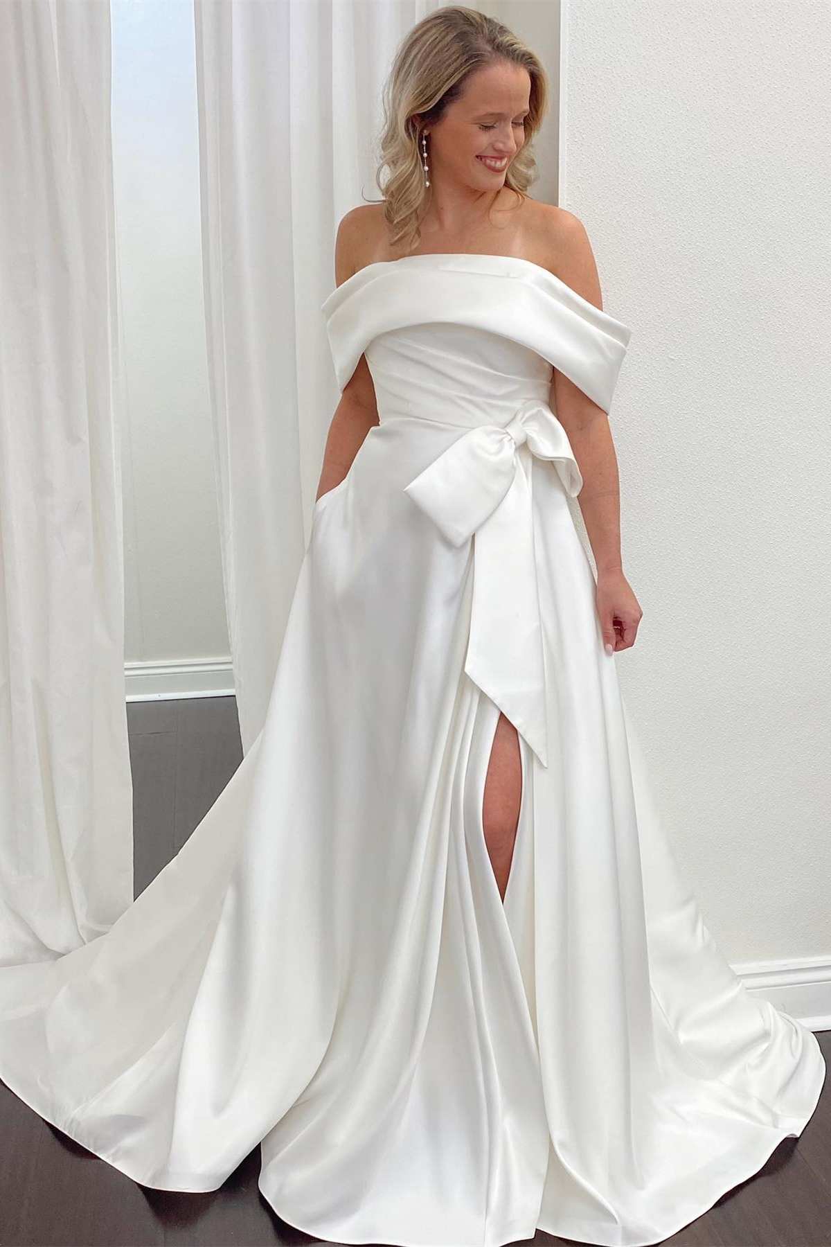 Vestido de novia de satén blanco con hombros descubiertos, lazo y abertura en forma de A