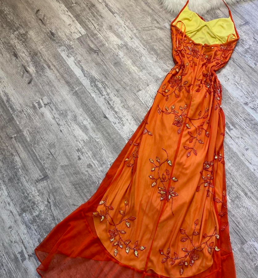 Vestido de fiesta único con tirantes finos en color naranja y cuentas, ideal para bodas formales.
