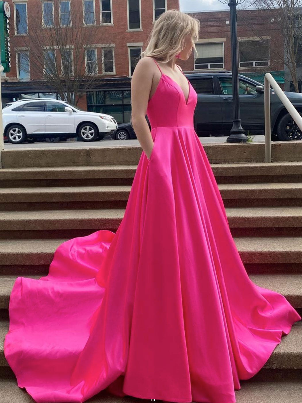 Vestido de fiesta largo de satén fucsia con escote en V y bolsillos.